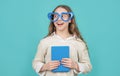 Happy girl back to school with book wearing big funny heart-shaped glasses blue background Royalty Free Stock Photo