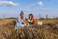 Happy girl best friends drink hot tea in mugs sitting on swamp dry grass in countryside