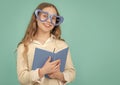 Happy girl in big funny heart-shaped glasses holding school book blue background Royalty Free Stock Photo