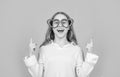 Happy girl in big funny heart-shaped glasses pointing fingers up blue background, copy space Royalty Free Stock Photo