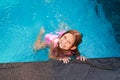 Happy girl with big smile enjoys summer fun in kids pool at resort. Child splashes in water, plays, content at tropical Royalty Free Stock Photo