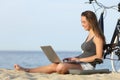 Happy girl with bike using laptop on the beach Royalty Free Stock Photo