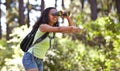 Happy girl, binoculars and pointing in nature with backpack for sightseeing, explore or outdoor vision. Young female Royalty Free Stock Photo
