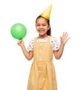 happy girl in birthday party hat blowing balloon Royalty Free Stock Photo