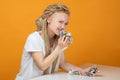 Happy girl bites off banknote, crumpled money in hands sitting at white table