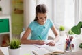 Happy girl with book writing to notebook at home Royalty Free Stock Photo