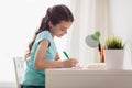 Happy girl with book writing to notebook at home Royalty Free Stock Photo