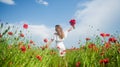 happy girl with bouquet of red flowers. summer vacation and holiday. pretty woman in white dress walking in poppy field Royalty Free Stock Photo