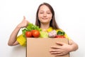 Happy girl with a box of vegetables in hands shows thumb up. Fresh and healthy food delivery concept. Proper nutrition in children