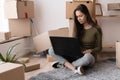 happy girl with boxes moves to new apartment, moving to a new house, rental housing, spanish young woman using laptop Royalty Free Stock Photo