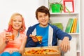 Happy girl and boy hold pizza pieces on white sofa Royalty Free Stock Photo