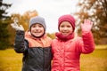 Happy girl and boy waving hands in autumn park