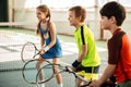 Happy girl and boys playing tennis