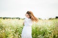 Happy girl on the camomile field, summer sunset. in a white dress. running and spinning, the wind in my hair, life style Royalty Free Stock Photo