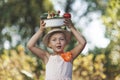 Happy girl carries homemade vegetables in a bowl on her head and laughs. Summer healthy food