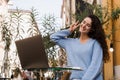 Happy girl chatting and gesticulates with family and friends via video call outdoor in cafe. Successful business woman Royalty Free Stock Photo