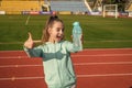 Happy girl child in activewear stand at sports stadium pointing finger at sport water bottle, hydration Royalty Free Stock Photo