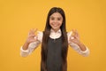 Happy girl child in school uniform smile gesturing double OK sings yellow background, okay Royalty Free Stock Photo