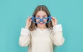 Happy girl child smiling in big funny heart-shaped glasses blue background Royalty Free Stock Photo