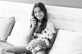 Happy girl child talk on cell phone sitting with toy puppy in bed, mobile call