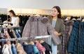 Happy girl chooses winter down jacket in clothing store Royalty Free Stock Photo