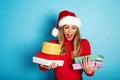 Happy girl with Christmas hat receives a lot of presents. Cyan background Royalty Free Stock Photo