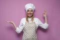 Happy girl cook in apron shows okay hand and smiles on a colored background, cheerful woman housewife in kitchen clothes Royalty Free Stock Photo