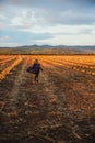 Happy girl in dark blue coat running on the pumpkin field