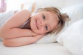 Happy girl daughter waking up smiling looking at camera on parent`s bed at morning. Happy relaxed family life with Royalty Free Stock Photo