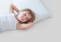 Happy girl daughter waking up smiling on parent`s bed at morning. Happy relaxed family life with children at home