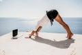 Woman sea laptop yoga. Business woman freelancer in yoga pose working over blue sea beach at laptop and meditates. Girl Royalty Free Stock Photo