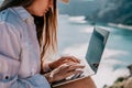 Woman sea laptop. Business woman in yellow hat freelancer with laptop working over blue sea beach. Girl relieves stress Royalty Free Stock Photo