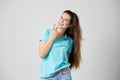 Happy girl dressed in light blue t-shirt smiles and shows rock sign
