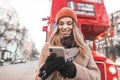 Happy girl dressed in warm clothes and a glove stands in the street with a smartphone in her hands, listens to music in the Royalty Free Stock Photo