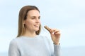 Happy girl eating cereal bar looking away on the beach Royalty Free Stock Photo