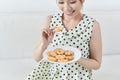 Happy girl eating a dietetic cookie sitting on a couch at home