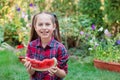 Happy girl eating watermelon in the garden. Kids eat fruit outdoors. Little girl playing in the garden biting a slice of water Royalty Free Stock Photo