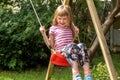 Happy girl, elementary school age child sitting swinging on an simple outdoor swing in the backyard, copy space, one person Royalty Free Stock Photo