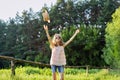 Happy girl enjoying summer vacation, kid in nature on green meadow playing with hat Royalty Free Stock Photo