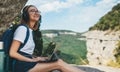 happy girl enjoys freedom in mountains listening to music on headphones and communication on digital tablet, traveler woman plan Royalty Free Stock Photo