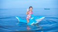 Happy girl swimming on an inflatable shark toy in the sea