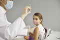 Happy little girl in a face mask waiting to get a vaccine at the doctor& x27;s office Royalty Free Stock Photo