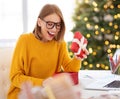 Happy girl freelancer opens a holiday gift at home office before Christmas