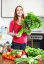 Happy girl with fresh vegetables and greens in kitchen Royalty Free Stock Photo