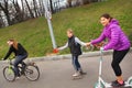 Happy girl friend ride roller skates scooter and bicycle on tow