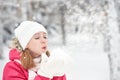 Happy girl on a frosty winter walk on street blows snow from hands Royalty Free Stock Photo