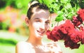 Happy girl in a garden with red roses. Beautiful young woman smelling a rose flower. Royalty Free Stock Photo