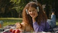 Happy girl gen z woman 20s female pet owner lying on grass with cute playful little dog corgi summer picnic in park Royalty Free Stock Photo