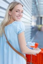 happy girl with groceries pushing cart on parking