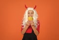 Happy girl on Halloween wear funny carnival costume and devil horns indoor holding pumpkin, halloween magic Royalty Free Stock Photo